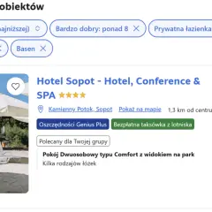 Białe leżaki i parasole na plaży przed budynkiem hotelu.