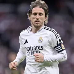 Chorwacki piłkarz Luka Modrić w białej koszulce Realu Madryt, z opaską kapitana na ramieniu, skupiony na grze.