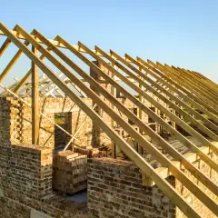 Budowa domu w toku. Widoczna drewniana konstrukcja dachu, czyli kalenica, co to jest? To najwyższa część dachu, łącząca jego połacie.