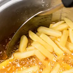 Frytki smażące się na głębokim oleju w metalowym garnku.