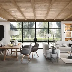 Rustikaler Holztisch mit grauen Stühlen, eine gemütliche Sofalandschaft und ein Bücherregal – perfekte esstisch inspo für ein helles Wohn-Esszimmer mit Blick ins Grüne.