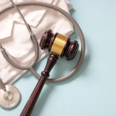 Martelletto da giudice e camice bianco con stetoscopio. Simboleggia la giustizia medica e la diagnosi sbagliata tumore.