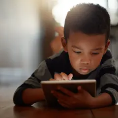 Un niño concentrado en su tablet, un ejemplo de cómo los niños introvertidos exploran mundos digitales.