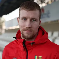 Młody piłkarz w czerwonej bluzie z herbem Korony Kielce, gotowy na nowe transfery.
