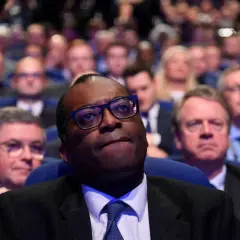 A man in glasses looks up, surrounded by a blurred audience. This scene captures a moment of collective attention, hinting at the shared experience and what is social impact.