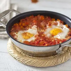 Un plat d'oeuf tomate mijoté dans une poêle, avec des poivrons et des épices. Un délice pour le petit-déjeuner.
