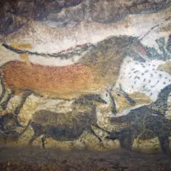 Przykłady malarstwa prehistorycznego: malowidła naskalne przedstawiające zwierzęta, takie jak konie i bizony, namalowane naturalnymi barwnikami na ścianie jaskini.