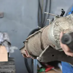 Mechanik trzyma zużyty filtr cząstek stałych. Zastanawiasz się, ile kosztuje wymiana filtra cząstek stałych?