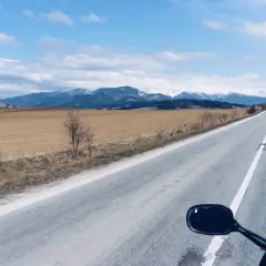 Motocykliści jadący drogą w kierunku ośnieżonych gór Tatr.