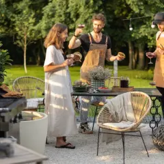 Przyjęcie w ogrodzie. Ludzie cieszą się burgerami i winem, a pies towarzyszy im w letnim popołudniu.