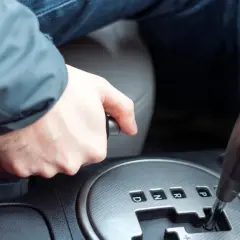 Main d'un conducteur actionnant le frein à main dans une voiture, prêt à démarrer.