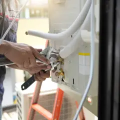 Técnico ajustando conexión para como cambiar el tubo de desague del aire acondicionado.