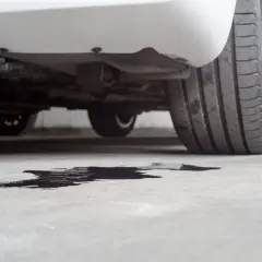 Macchia scura sul cemento sotto un'auto, probabile perdita liquido radiatore.