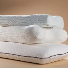 Drei weiße Kissen stapeln sich. Das oberste Kissen hat blaue Linien. Ein guter Schlaf ist wichtig, wie der derila kopfkissen test stiftung warentest zeigt.