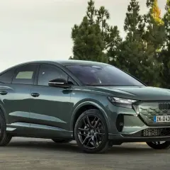 Der **Audi Q4 Facelift** in elegantem Grün steht vor Bäumen. Sein sportliches Design mit coupéhafter Dachlinie und markanten Felgen macht ihn zum Hingucker.