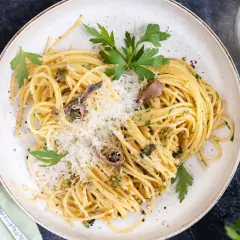 Spaghetti mit Sardellen, Kapern und Parmesan, garniert mit Petersilie. Ein köstliches Gericht, das Meer und Land vereint.