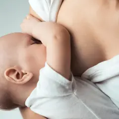 Zbliżenie na dziecko karmione piersią przez matkę.