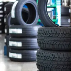 Stosy nowych opon chińskich w magazynie. Widać bieżnik i etykiety z informacjami.