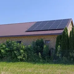 Panele fotowoltaiczne na dachu ceglanego budynku, symbolizujące sprzedaż energii z fotowoltaiki.