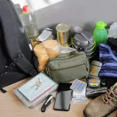 Plecak na wypadek wojny zawiera wodę, konserwy, ciastka, ubrania, buty, apteczkę, telefon, klucze i narzędzia.