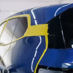 Błękitny lakier samochodu BMW zabezpieczony żółtą folią ochronną przed pracami detailingowymi.