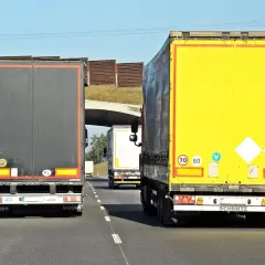 Na autostradzie jadą trzy tiry. Znak ograniczenia prędkości wskazuje, że tiry mogą jechać 70 lub 80 km/h.