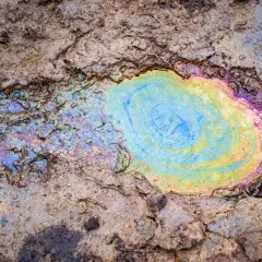 Tęczowa plama oleju na ziemi, która pokazuje, czy olej się psuje. Kolory mienią się na powierzchni.