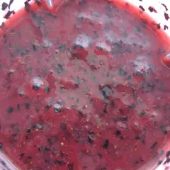 Gęsty, purpurowy mus z czarnej porzeczki, z widocznymi kawałkami owoców i pęcherzykami powietrza, gotowy do podania.