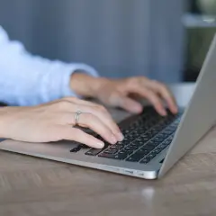Mani su tastiera di un laptop, con anello nuziale. Lavoro da remoto per ottenere myecm crediti.