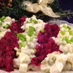 Pyszna sałatka z burakiem i śledziem, udekorowana szczypiorkiem, na tle świątecznej choinki.