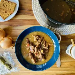 Carbonade flamande mijotée dans un Cookeo, servie dans un bol bleu avec du pain de seigle.