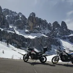 Due moto pronte per affrontare i passi bergamaschi innevati, con imponenti vette rocciose sullo sfondo.