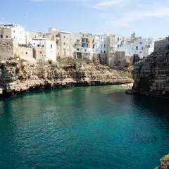 Un estany gento con aguas cristalinas rodea un pueblo blanco construido sobre acantilados rocosos.