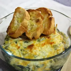 Delicioso plato de espinacas con bechamel gratinado, coronado con tostaditas de pan.