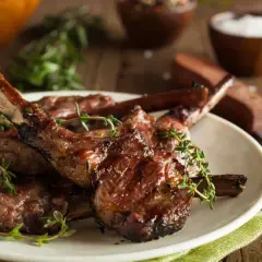 Délicieuses côtelettes d'agneau grillées, garnies de thym frais, prêtes à être dégustées.