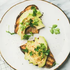 Deux toasts avec avocat tranché, persil frais et une pincée d'épices. Un avocat avec quoi, un délice simple et sain.