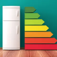Biała lodówka obok kolorowej drabinki energetycznej pokazuje, ile prądu potrzebuje lodówka.
