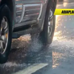 Un coche sufre aquaplaning en un día lluvioso, levantando agua al pasar.