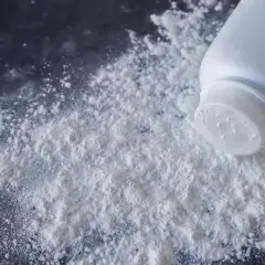 Un flacone di borotalco rovesciato su una superficie scura, creando una nuvola bianca. Forse le formiche lo evitano.
