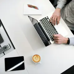 Kto to jest administrator? To osoba pracująca przy laptopie, z telefonem Cisco, tabletem i kawą.