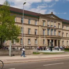 Großes Universitätsgebäude mit Brunnen und Studenten. Hier kann man Zahnmedizin studieren.