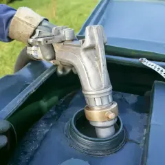 Ręka w rękawicy trzyma pistolet do tankowania, wlewając paliwo. Czy to mazut? Co to jest?