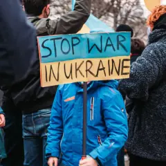 Kind hält Schild "Stop War in Ukraine". Ein starkes Bild, das an die Stimmen im Ukraine Podcast erinnert, die Frieden fordern.