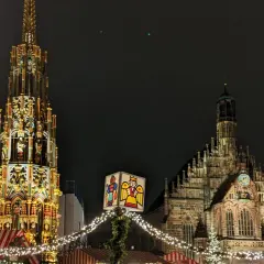 Nocne jarmarki bożonarodzeniowe w Europie. Wspaniała iluminacja zabytkowej fontanny i kościoła, ozdobione świątecznymi lampkami i dekoracjami.