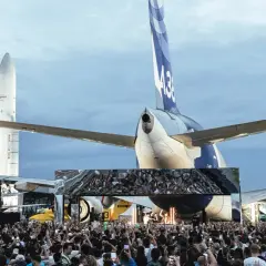 Foule immense devant une scène, sous des avions et des fusées. Ambiance de festival Cercle.