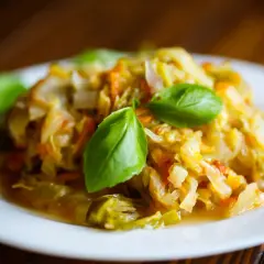 Pyszny bigos z młodej kapusty, duszony z marchewką i przyprawami, udekorowany listkami bazylii. Idealny przepis, jak ugotować dobry bigos z młodej kapusty.