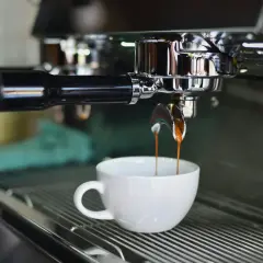 Macchina da caffè professionale eroga un espresso in tazza bianca. Il consumo di una macchina del caffè da bar varia, ma questa è un'immagine iconica.