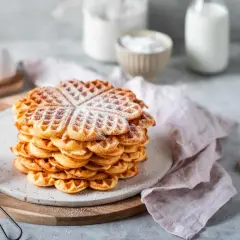Ein Stapel Herz-Waffeln, bestäubt mit Puderzucker. Perfekt für ein Frühstück, das mit dem Thermomix zubereitet wurde.