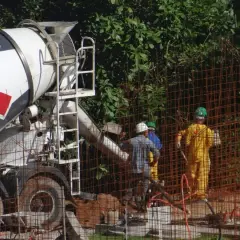Betoniarka dostarcza beton na budowę. Zastanawiasz się, ile kosztuje metr betonu z betoniarki? Pracownicy w kaskach nadzorują rozładunek.