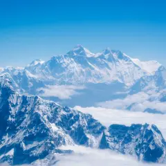 Majestatyczne, ośnieżone szczyty Himalajów, gdzie leży Mount Everest, wyłaniają się z morza chmur pod błękitnym niebem.